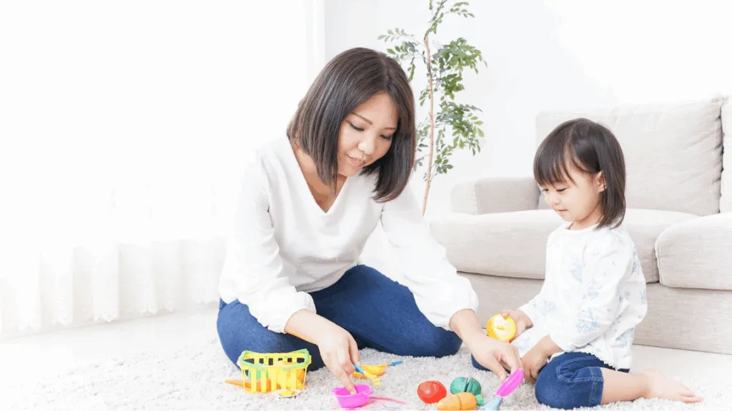 mom patiently guide her little girl while playing toys