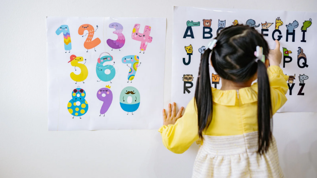 toddler girl pointing alphabet letters on the wall